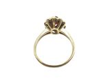 a close up of a gold ring with a red stone