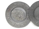 two metal plates with designs on them on a white surface