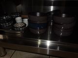 several bowls and cups are sitting on a shelf in a kitchen