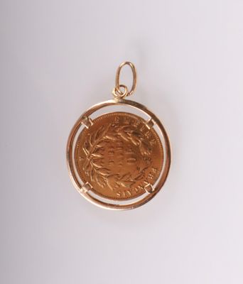 un gros plan d'une pièce de monnaie sertie dans un pendentif en or, posée sur une surface blanche