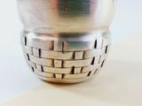 a silver vase with a woven design on it