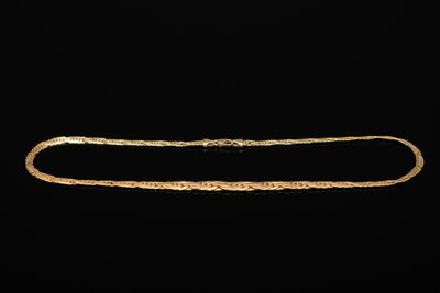 un collier en or à longue chaîne sur fond noir