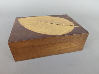 une petite boîte en bois ornée d'une feuille