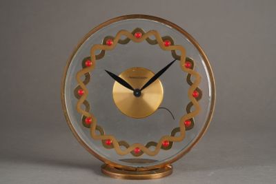 une horloge dorée ornée de perles rouges, posée sur une table
