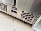 a stainless steel refrigerator with a door open on a tiled floor