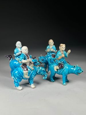 three figurines of people riding on horses with a dog