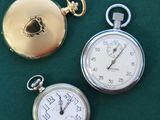 three different types of pocket watches on a green surface
