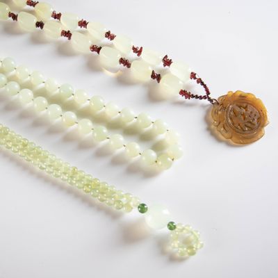 a white bead necklace with green beads on a white table