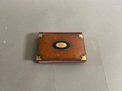 une image représentant une petite boîte en cuir marron ornée d'une plaque dorée