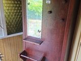 une porte en bois sur laquelle est accroché un miroir, dans un coin de la pièce