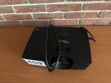 a small projector sitting on a table with a brick wall behind it