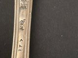 an antique silver spoon with writing on it sitting on a black surface