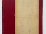 un vieux livre à la couverture rouge posé sur une surface blanche