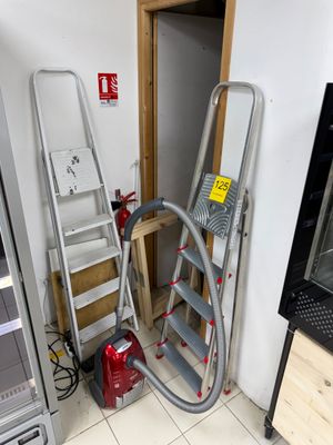 Plusieurs échelles sont empilées les unes sur les autres dans une pièce.