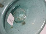 a green vase with a tag on it sitting on a table
