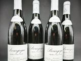 quatre bouteilles de vin sont alignées sur un support en bois