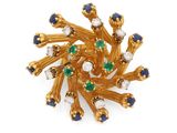 un gros plan sur une broche en or sertie de pierres bleues et vertes