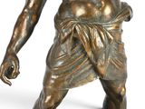 bronze statue of a man holding a knife in his right hand