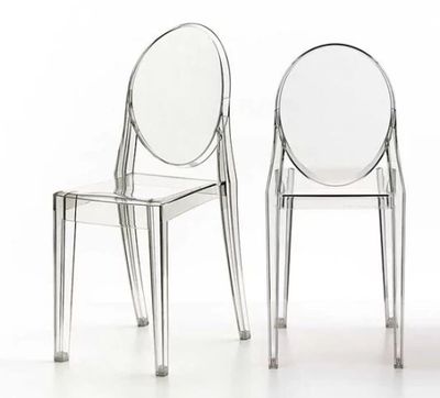 deux chaises en plastique transparent placées l'une à côté de l'autre sur une surface blanche