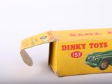 a green toy car in a yellow box on a white surface