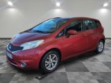 a red nissan versa parked on a checkered tile floor
