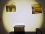 two paintings hanging on the wall above a small table