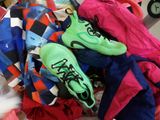 a pile of clothes and a pair of shoes on a bed