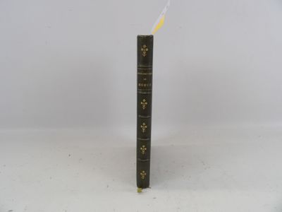 un vieux livre posé sur une table à côté d'un mur blanc