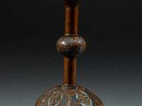 un vieux bougeoir en bronze orné d'un motif floral sur le dessus
