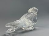 crystal figurine of a bird on a stand on a gray surface