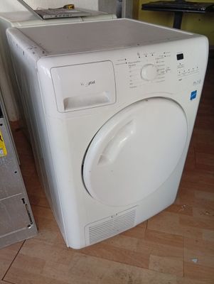 a white washing machine sitting on the floor next to a laptop