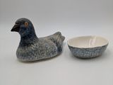 a bird sitting next to a bowl on a table