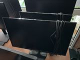 three monitors sitting on a desk in front of a window