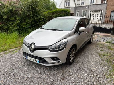 La voiture argentée est garée devant une maison au bord de la route.