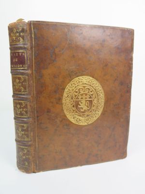 un vieux livre marron orné d'un médaillon doré sur la couverture