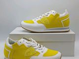 une paire de baskets jaunes et blanches posée sur une boîte