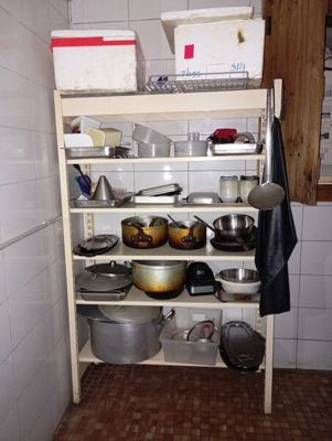 de nombreuses casseroles et poêles sur une étagère dans la cuisine