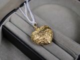 un pendentif en or en forme de cœur posé dans un écrin