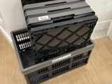 three black plastic crates stacked on top of each other on a wooden floor