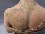 a clay statue of a woman with her back to the camera