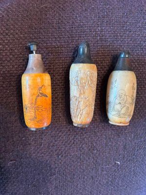 Trois bouteilles de couleurs différentes sont alignées sur une surface marron.