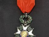 un gros plan d'une médaille posée sur une surface noire, avec un ruban rouge