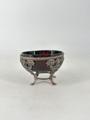 an antique silver plate with a red glass bowl on a stand
