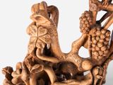 carved wood sculpture of a dragon with grapes on it ' s back