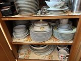 many plates and cups stacked on a shelf in a cabinet