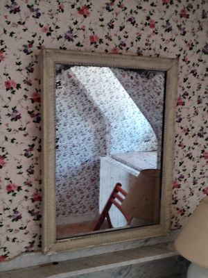 un miroir dans un coin d'une pièce où se trouvent une chaise et une lampe