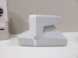 a white stapler sitting on a desk next to a phone