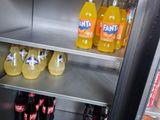 bottles of soda and soft drinks sit on shelves in a refrigerator