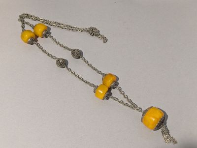 un collier composé de perles jaunes montées sur une chaîne, posé sur une table