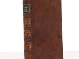 an old book with a brown cover sitting on top of a table
